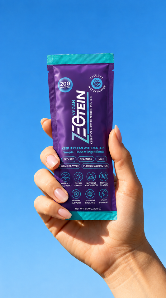 A hand holding up a Zeotein single serve stick pack against a clear blue sky