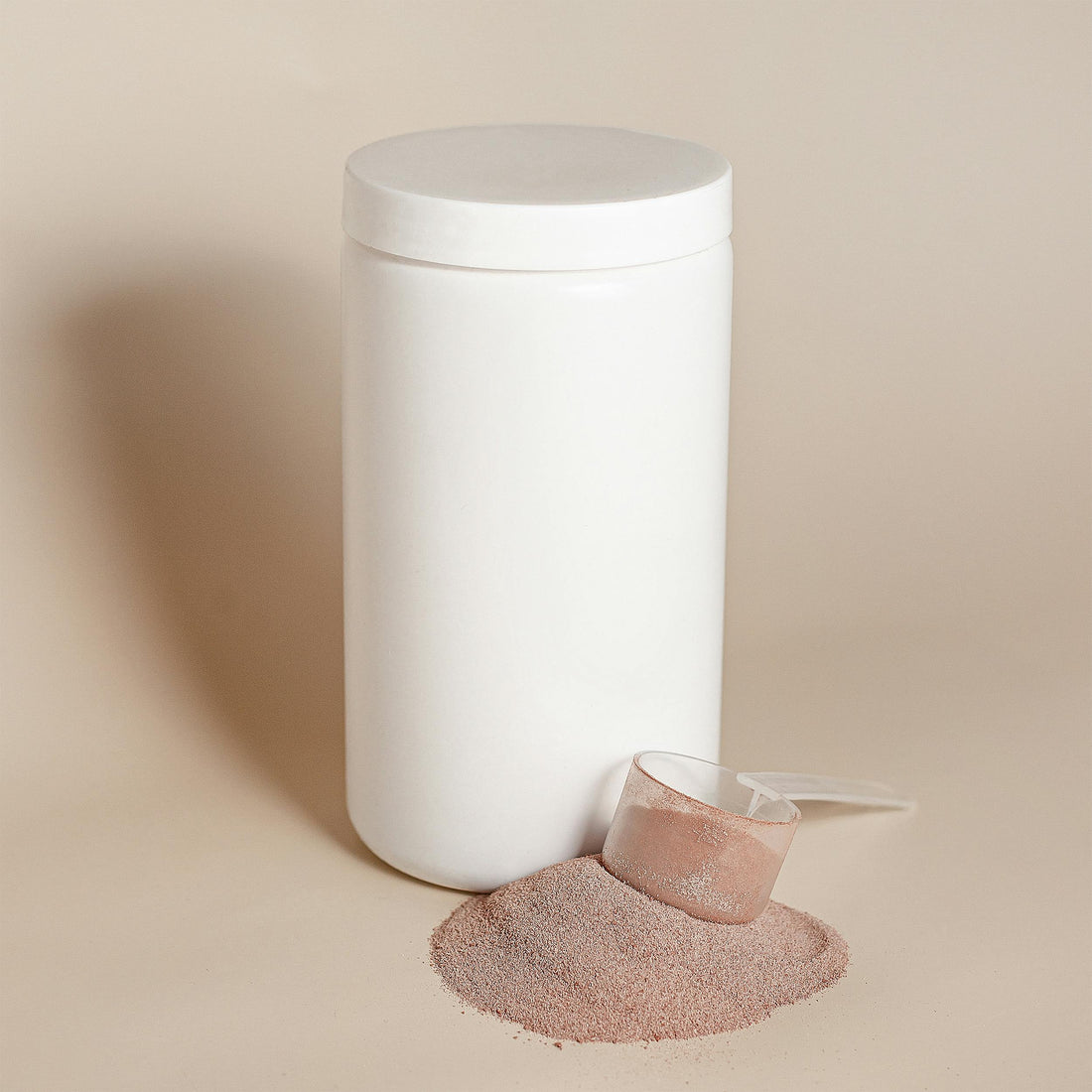 A plain white protein powder container with a scoop of powder spilled beside it on a neutral background